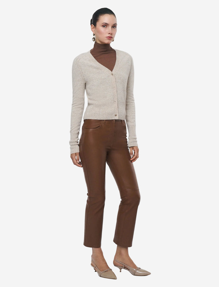 Woman wearing a beige cardigan and brown pants on a white background