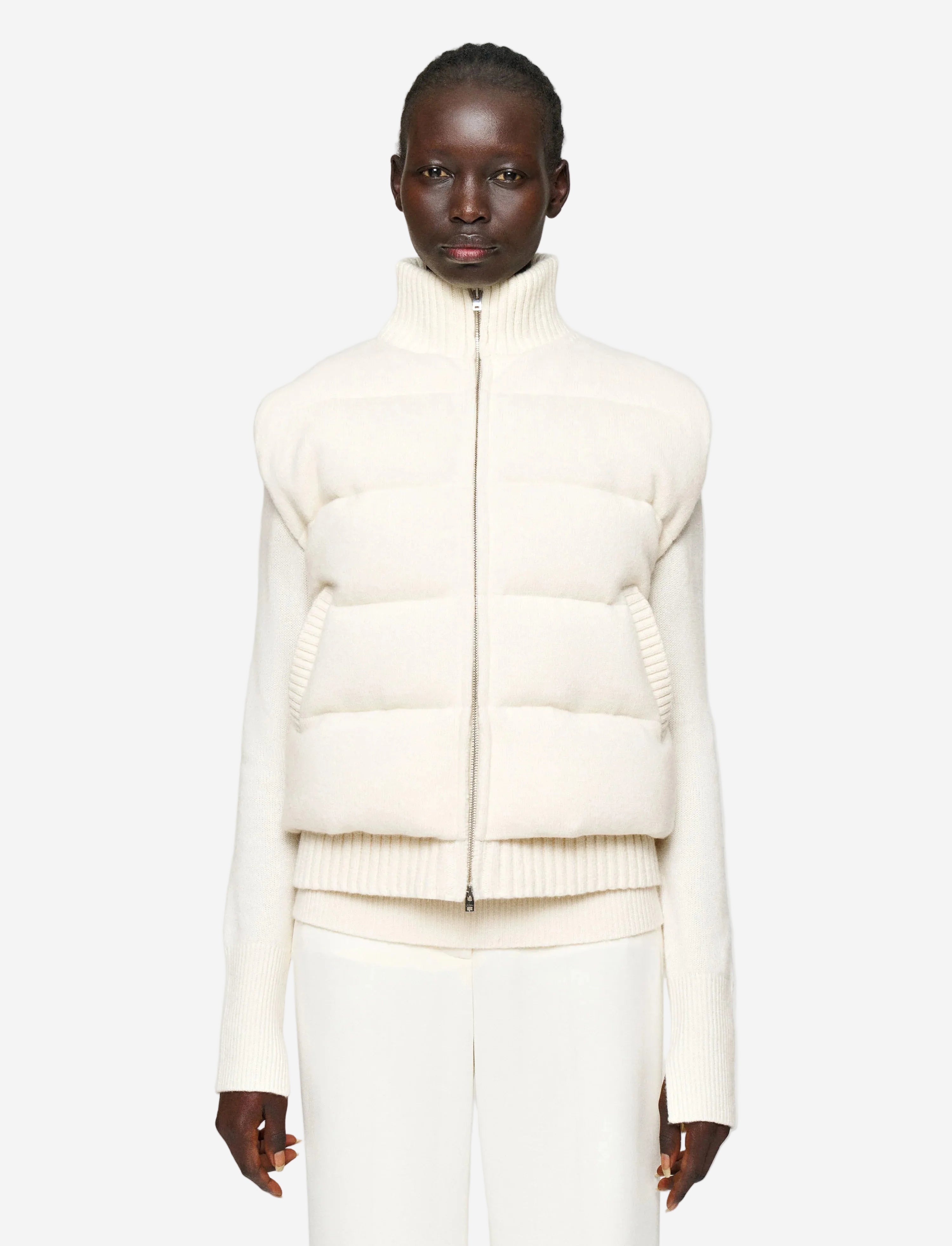 Person wearing a white puffer jacket on a plain background
