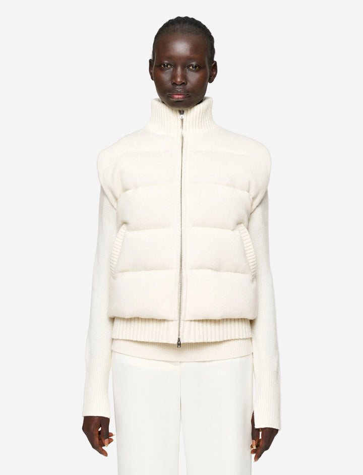 Person wearing a white puffer jacket on a plain background