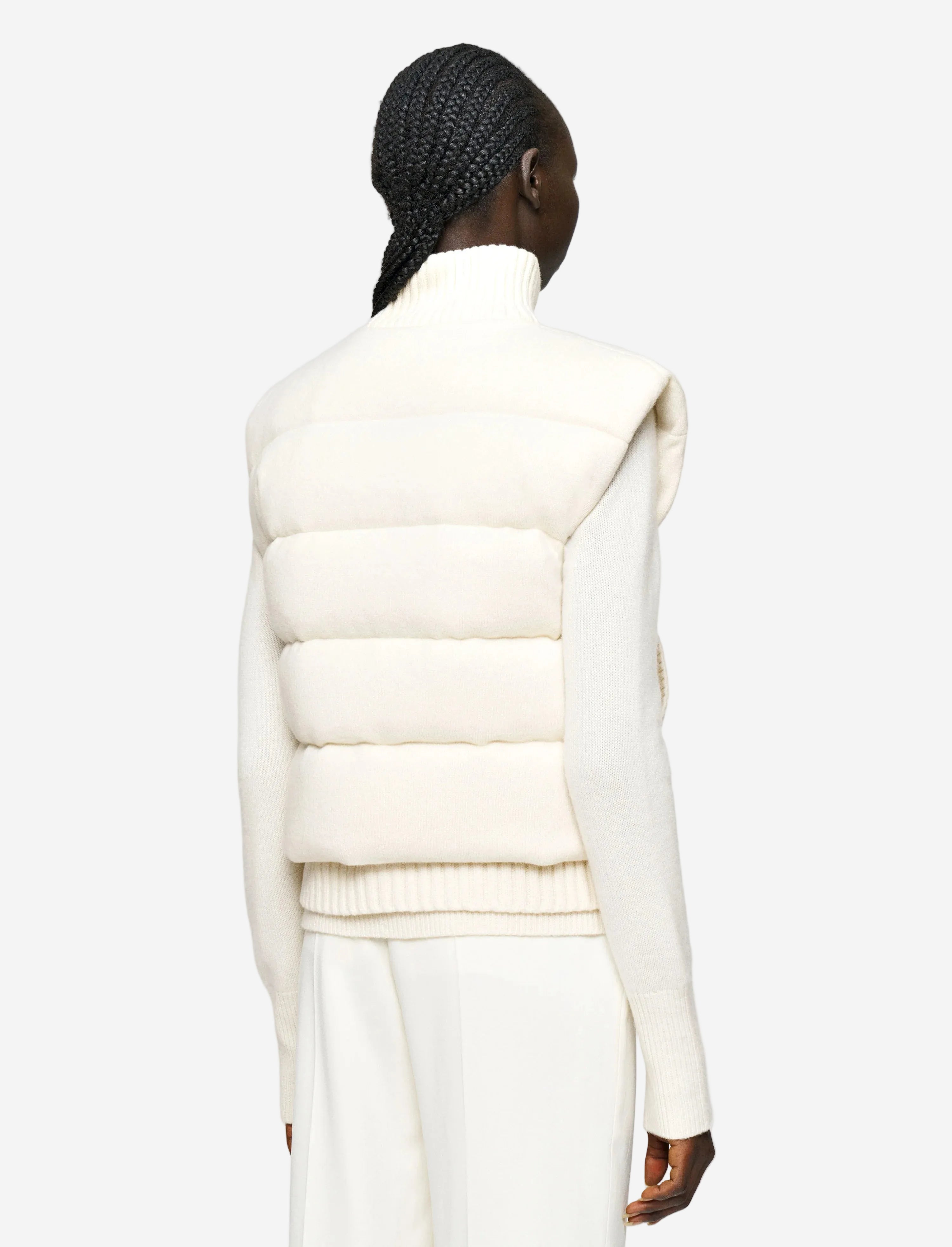 Person wearing a white puffer vest on a plain background