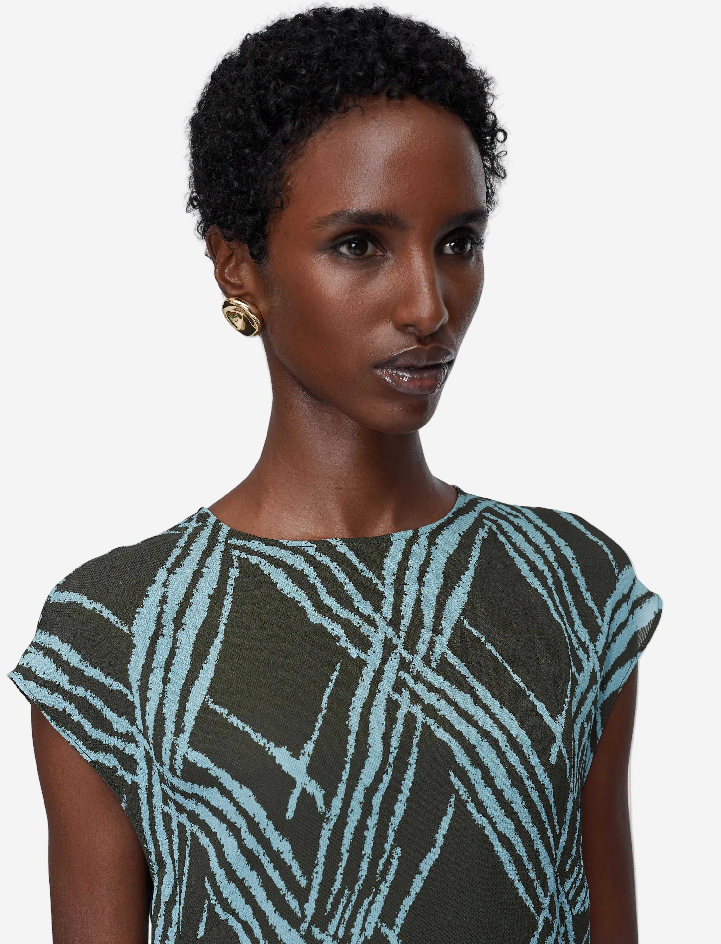 Woman wearing a patterned dress against a plain background