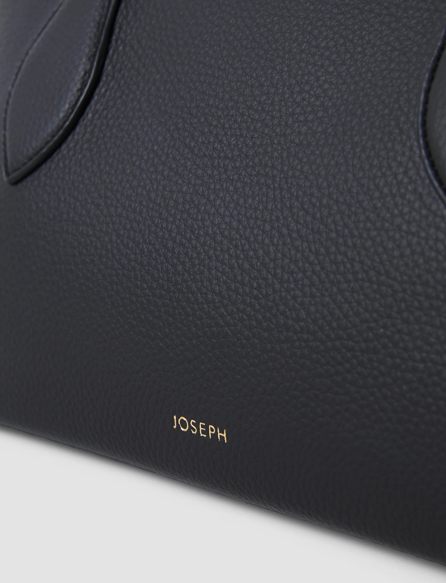 Close-up of a black leather product with 'JOSEPH' branding on a light gray background