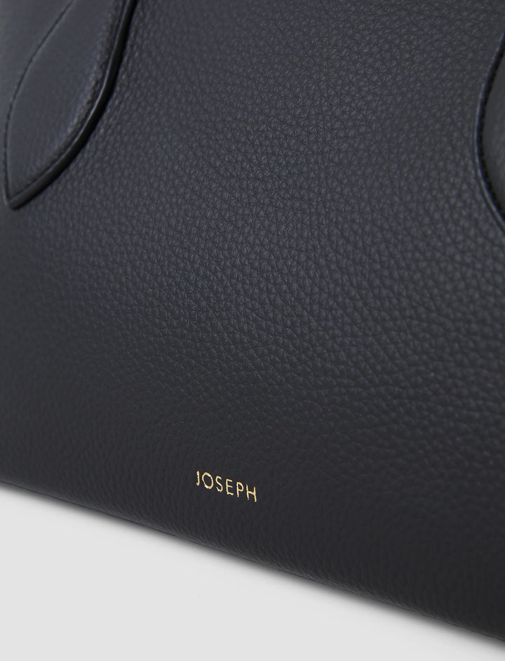Close-up of a black leather product with 'JOSEPH' branding on a light gray background