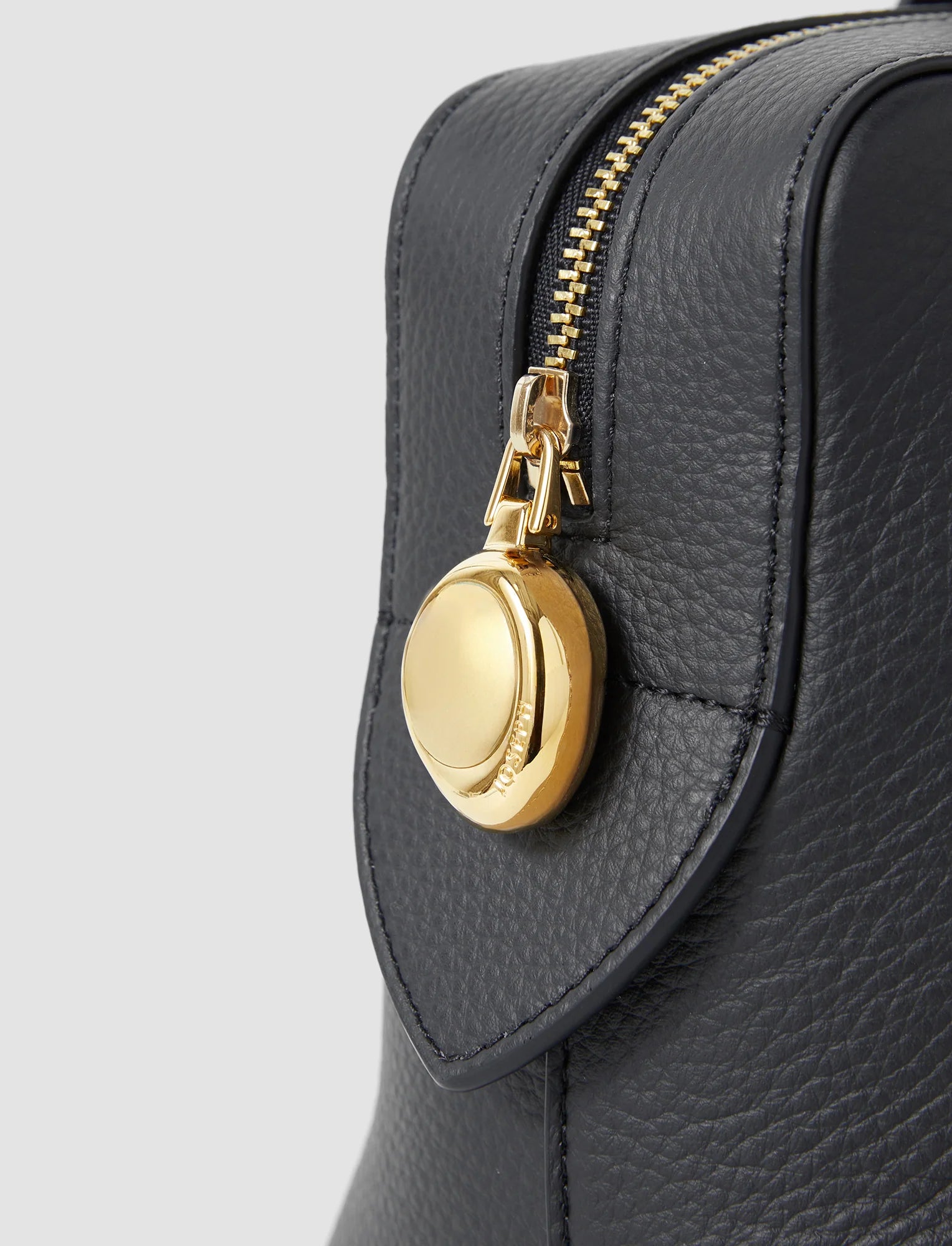 Black leather pouch with a gold zipper on a light gray background