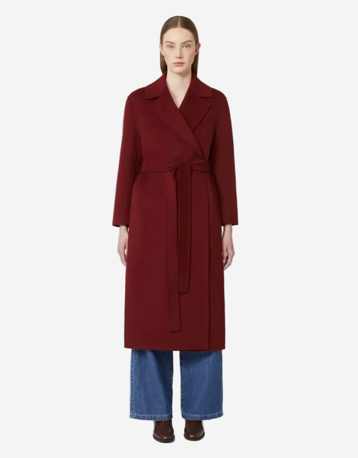 Woman wearing a long burgundy coat with a white background