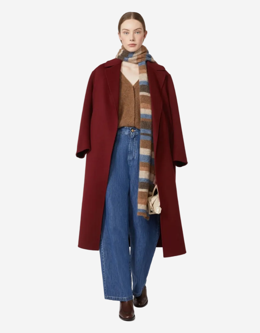Person wearing a red coat, brown sweater, blue jeans, and a patterned scarf on a white background