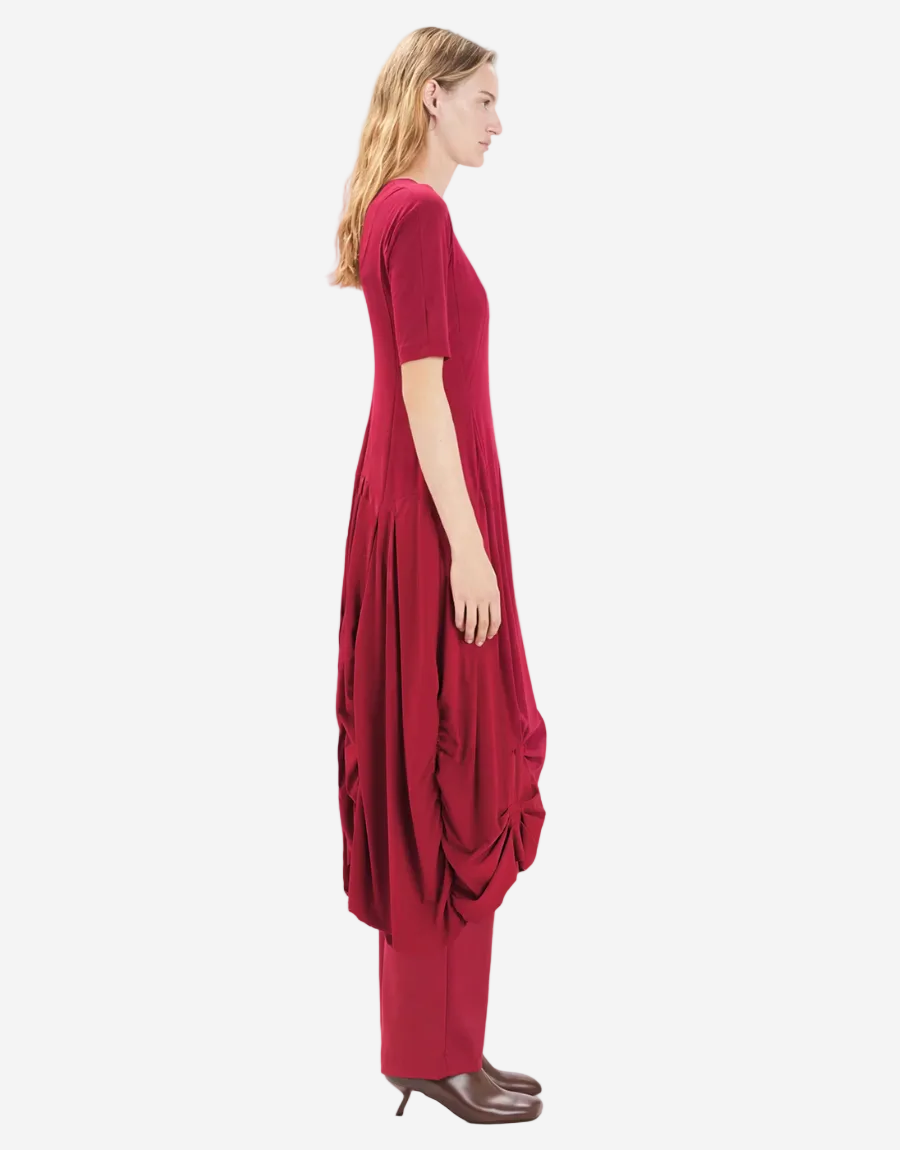 Woman wearing a red dress with a draped design on a white background