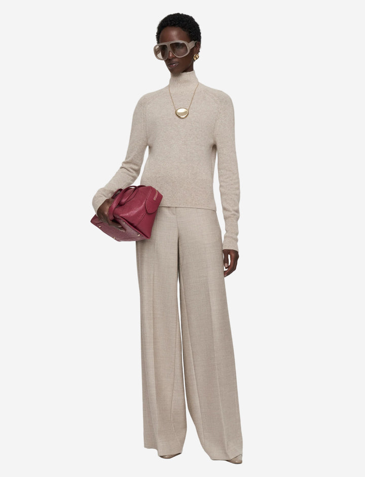 Woman wearing a beige outfit with a red handbag on a white background