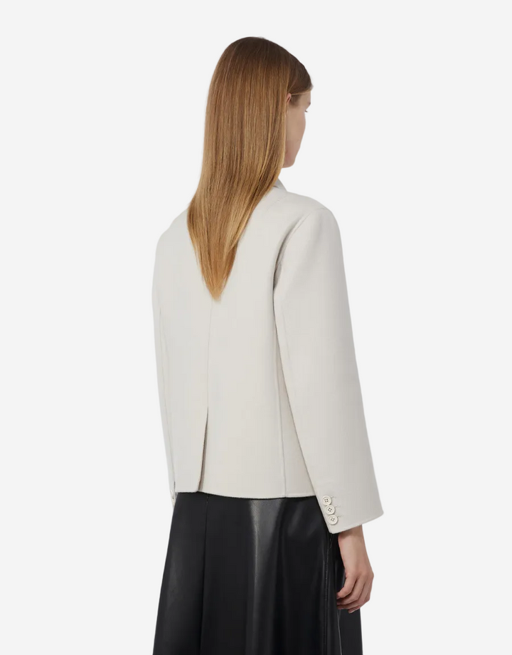 Woman wearing a white blazer and black pants on a white background