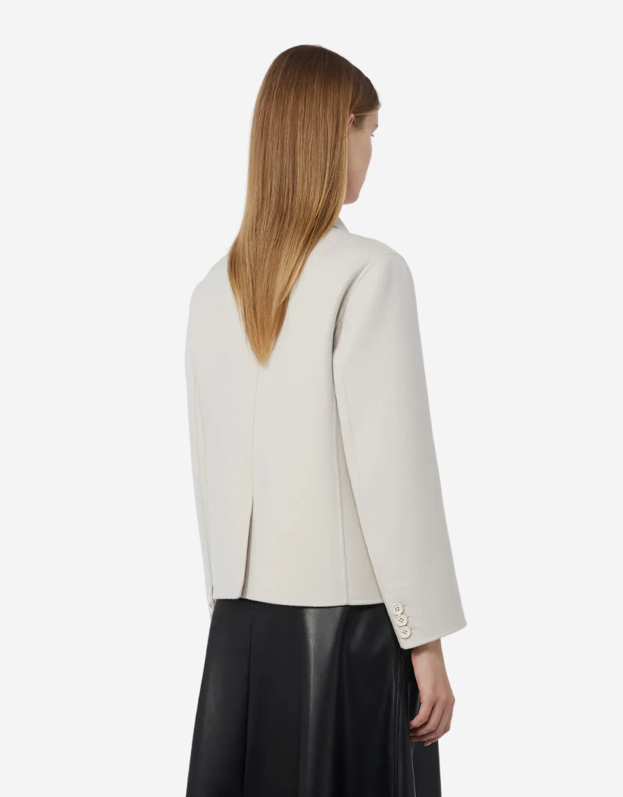 Woman wearing a white blazer and black pants on a white background