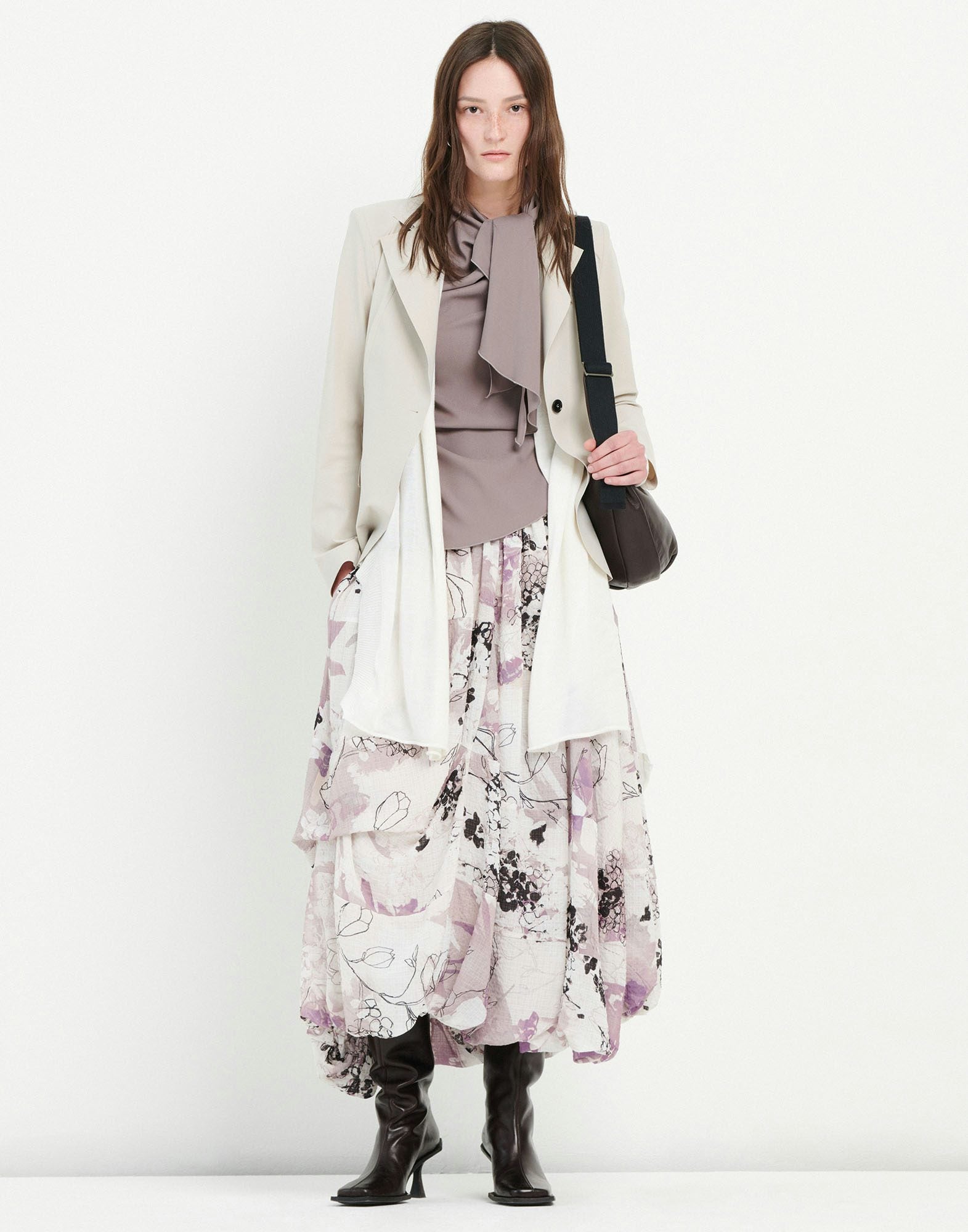 Woman wearing a light green blazer over a patterned dress on a white background