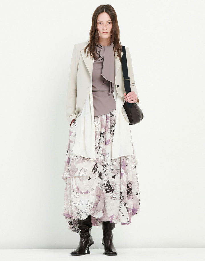 Woman wearing a light green blazer over a patterned dress on a white background