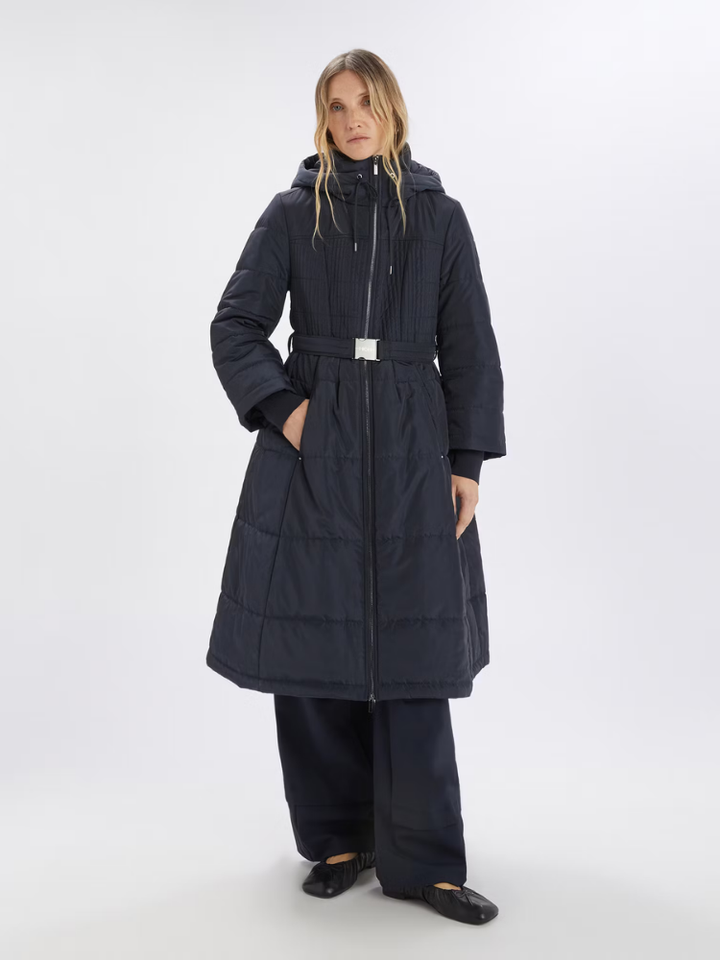 Woman wearing a long black coat on a white background