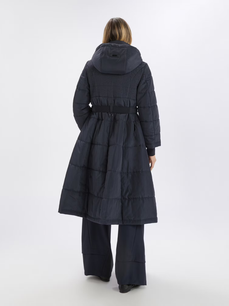 Person wearing a long dark blue quilted coat on a white background