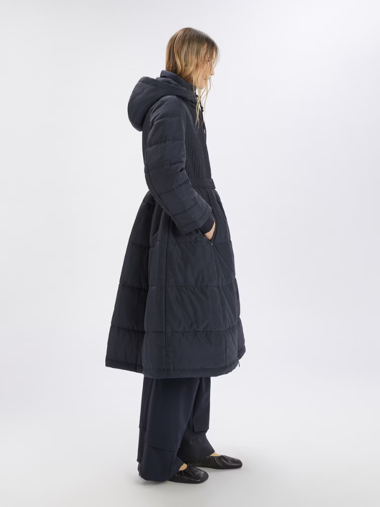 Person wearing a long dark coat on a white background