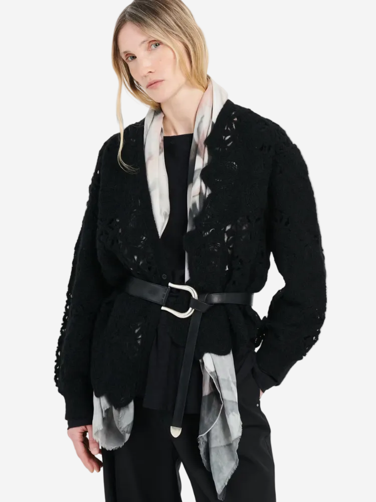 Woman wearing a black textured jacket with a patterned scarf against a white background