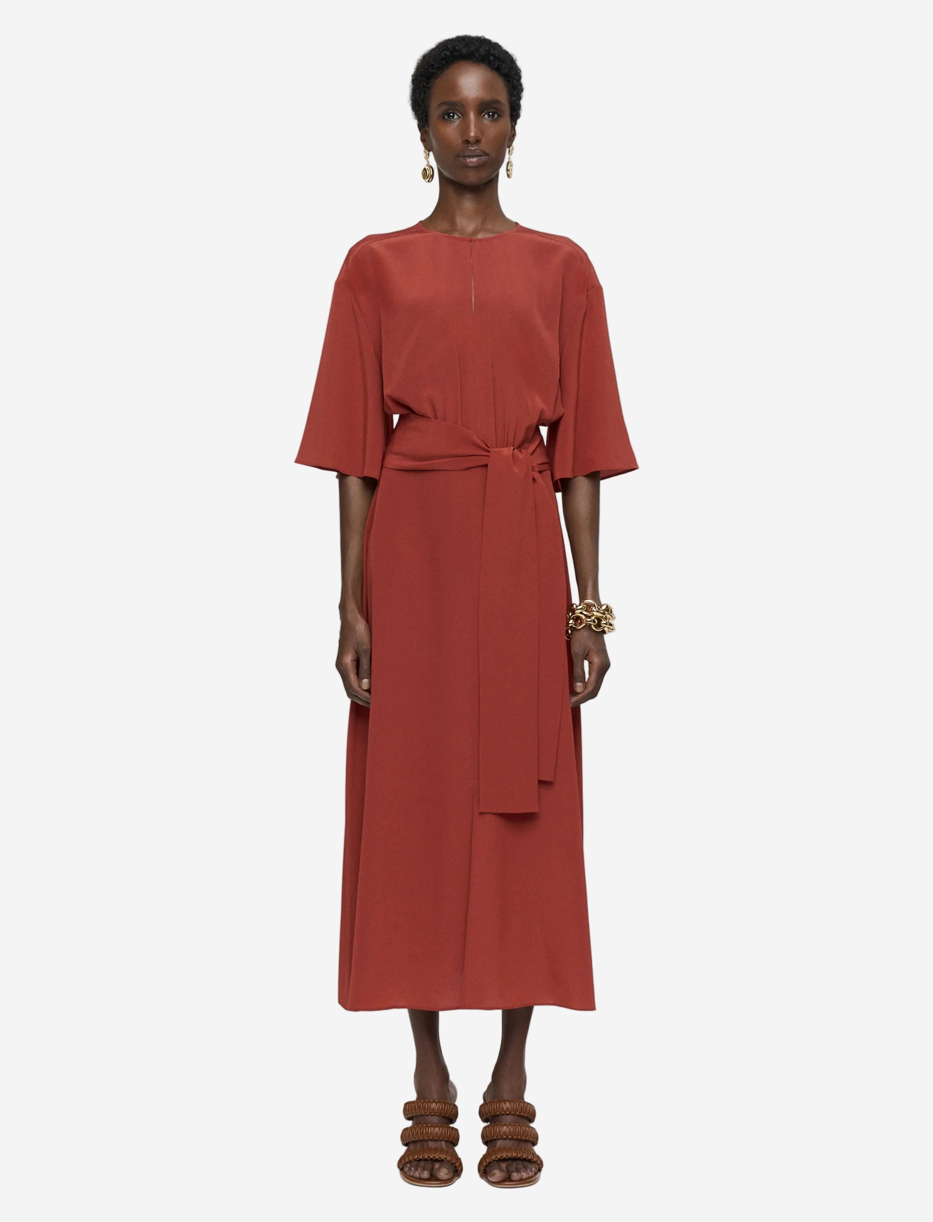 Woman wearing a rust-colored dress on a light gray background