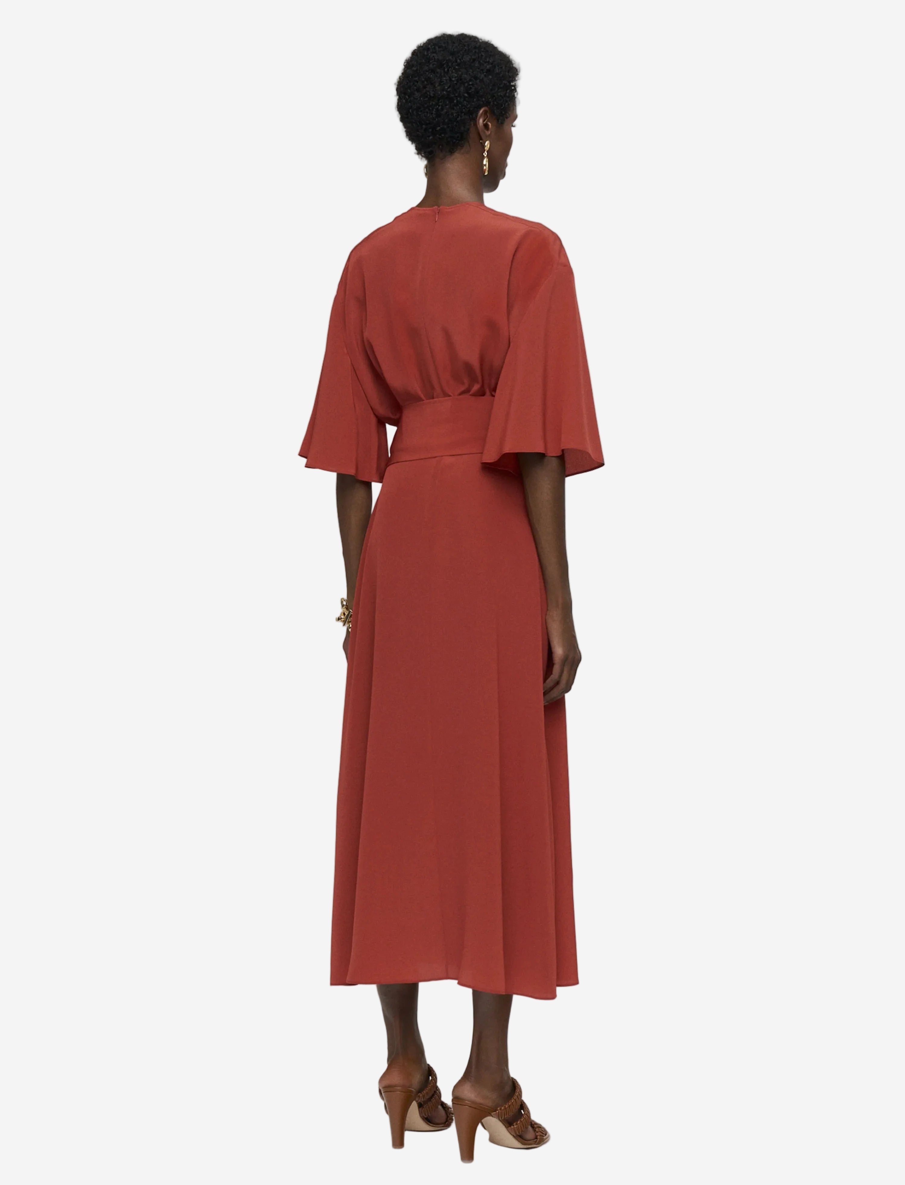 Woman wearing a rust-colored dress with a plain background