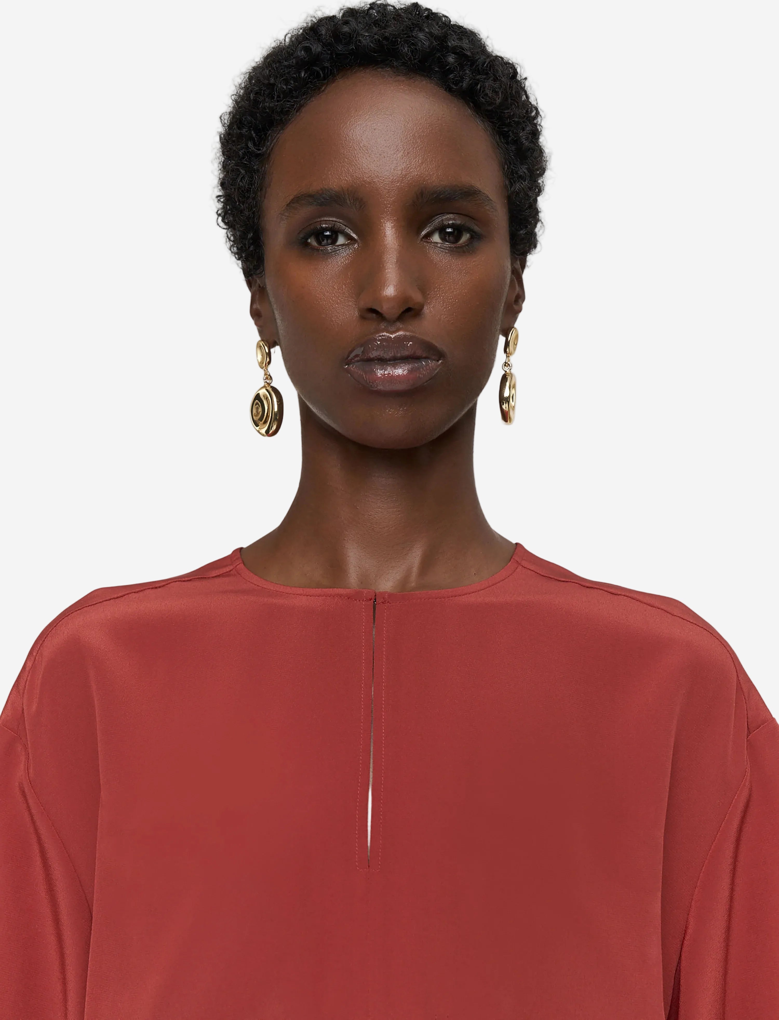 Woman wearing a rust-colored top against a plain background