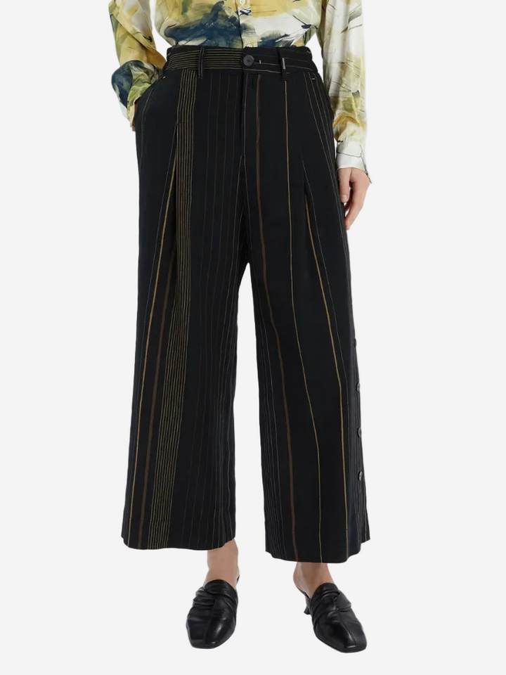 Black wide-leg pants with gold stripes worn by a person on a white background