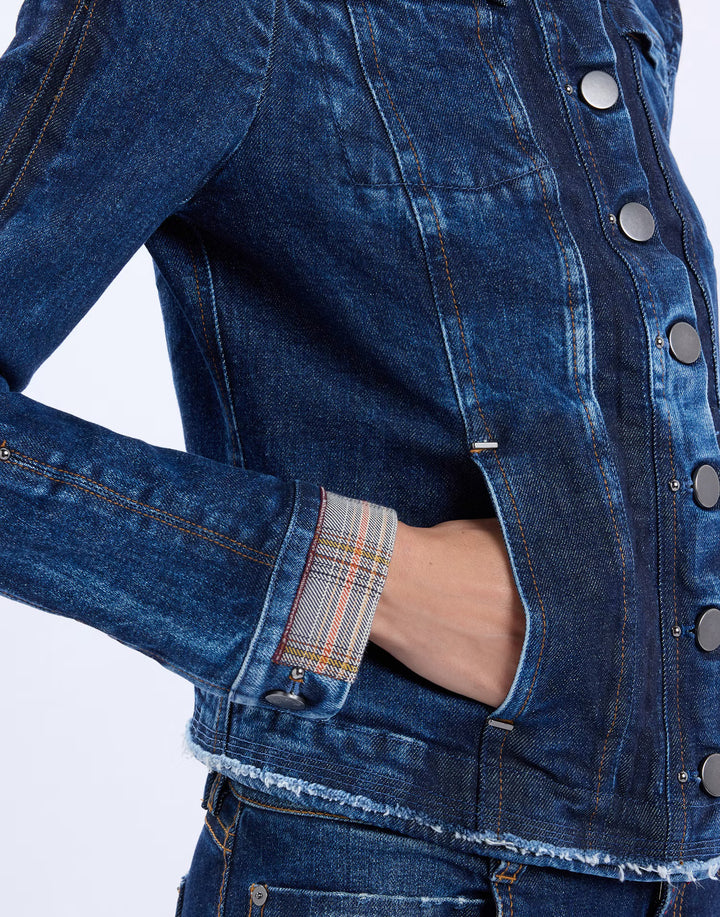 Close-up of a dark blue denim jacket with a frayed hem, silver-tone buttons, and a plaid lining visible in the pocket.
