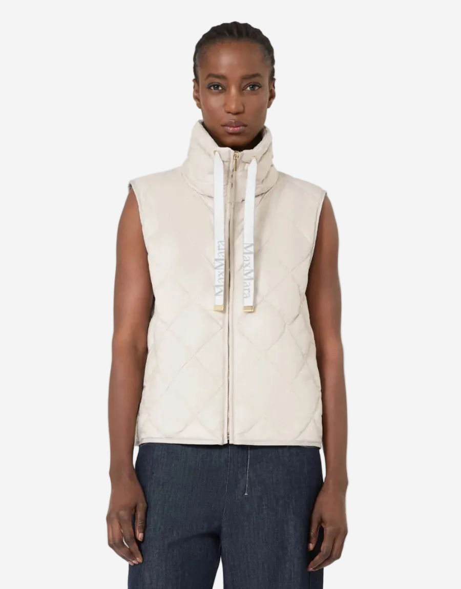 Person wearing a beige quilted vest on a white background