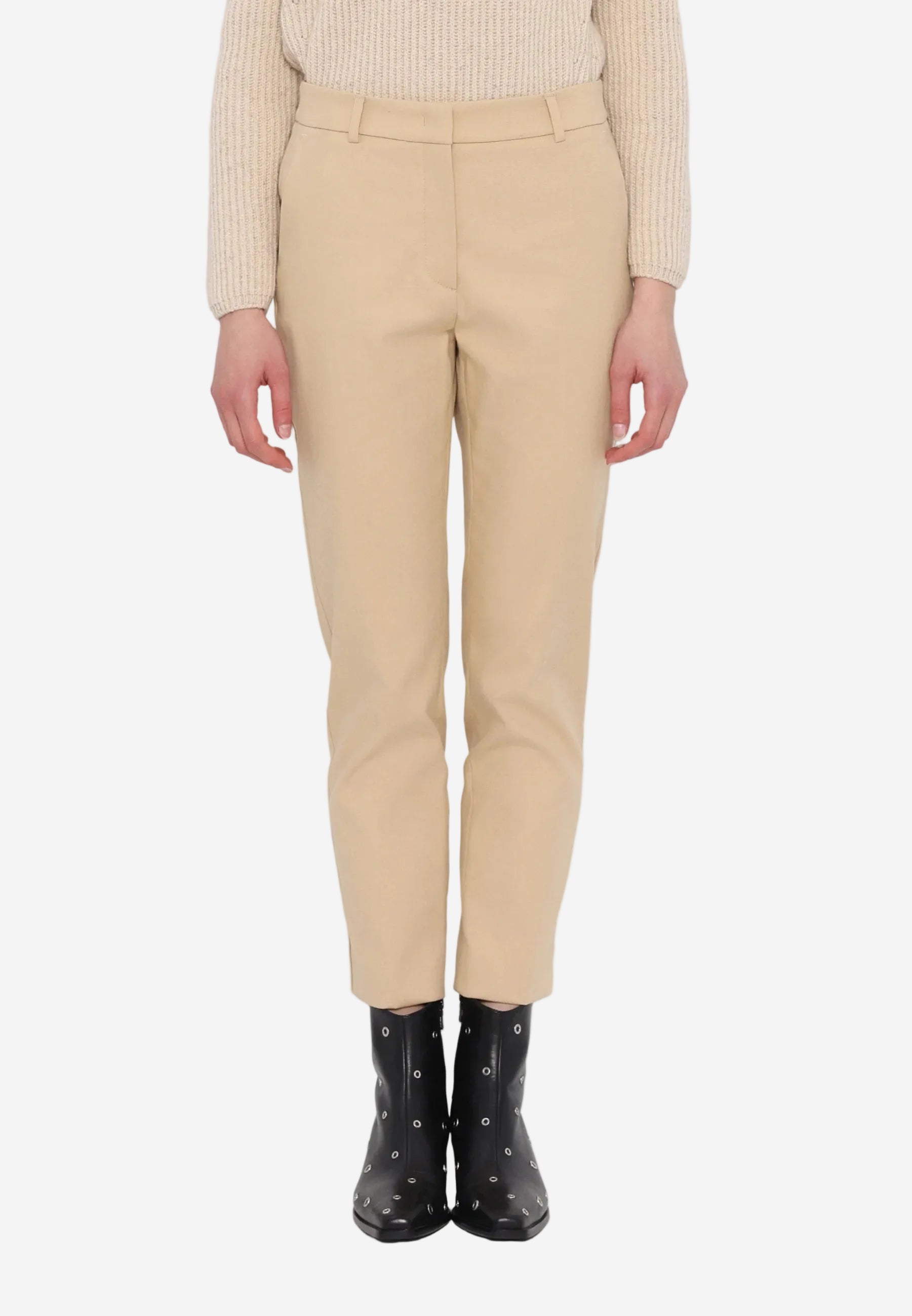 Person wearing beige pants and black rain boots on a white background