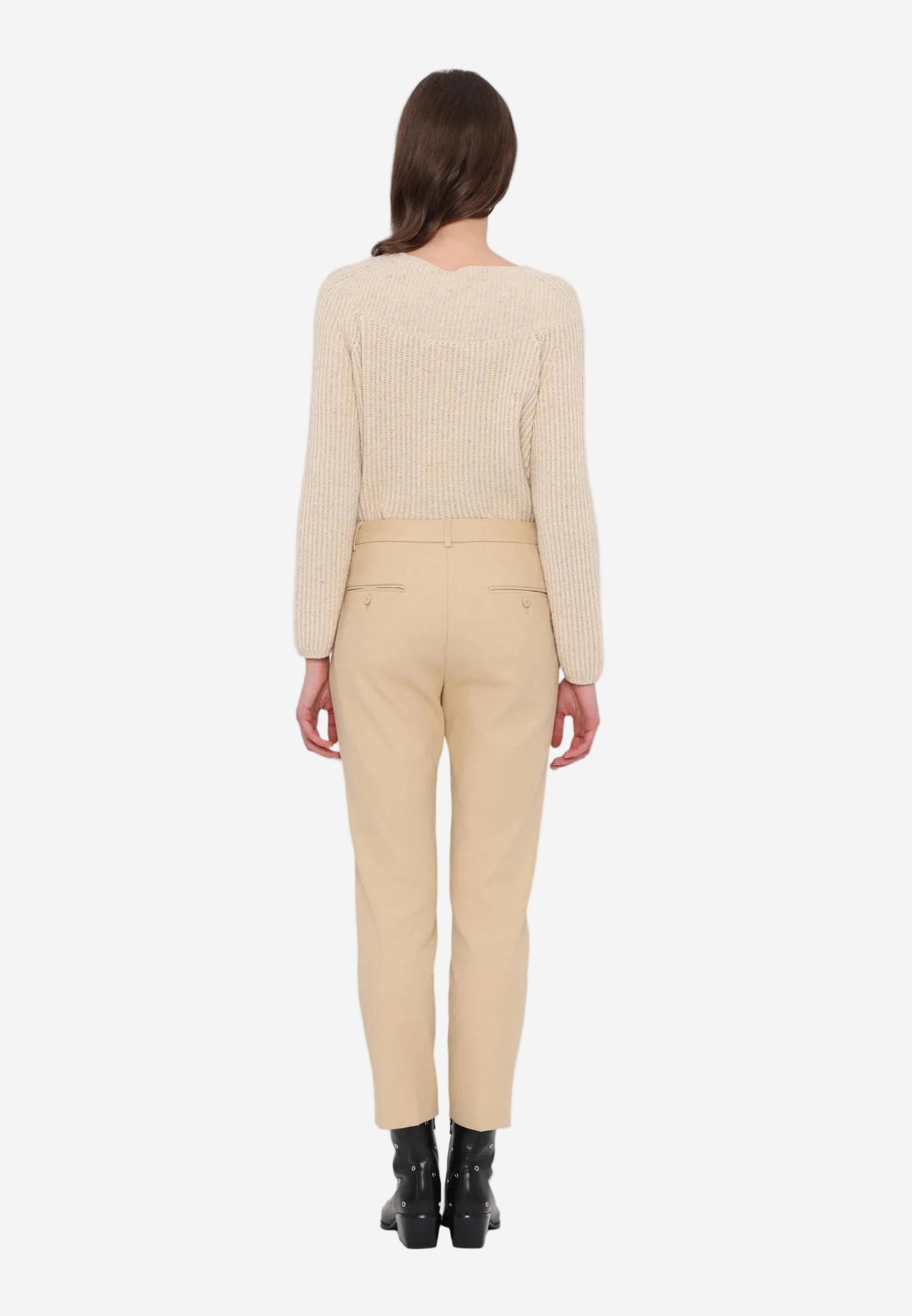 Person wearing a beige sweater and pants on a white background