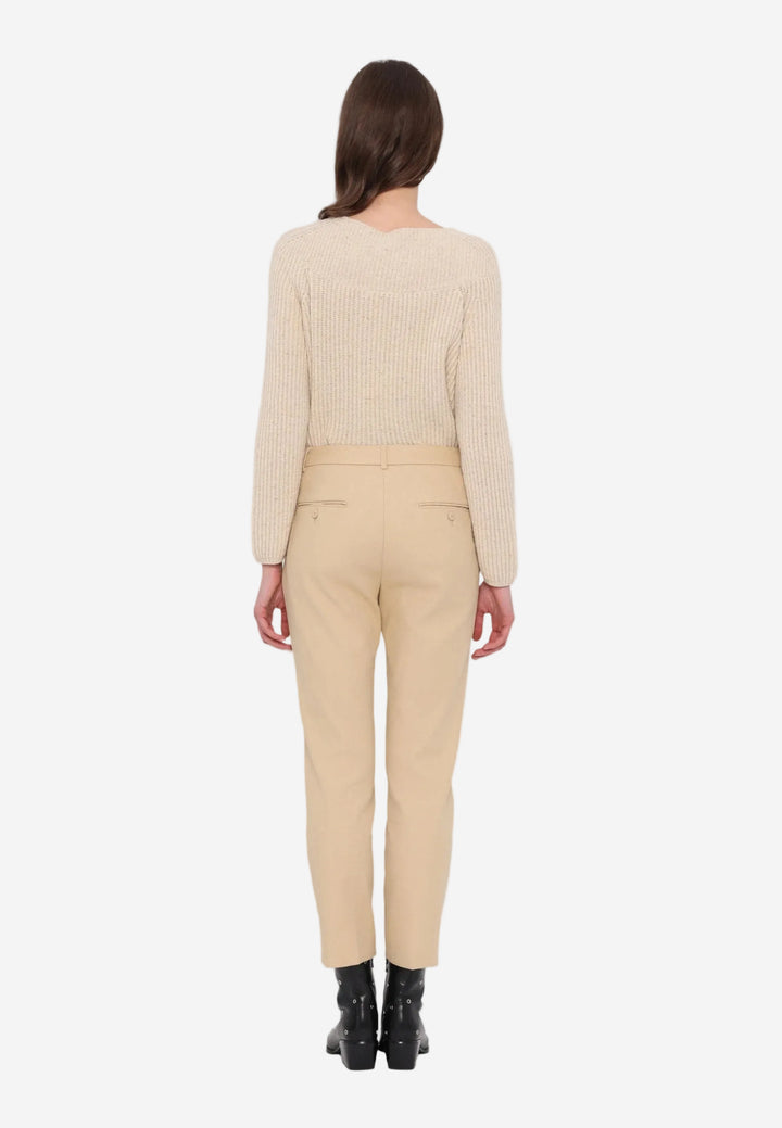 Person wearing a beige sweater and pants on a white background