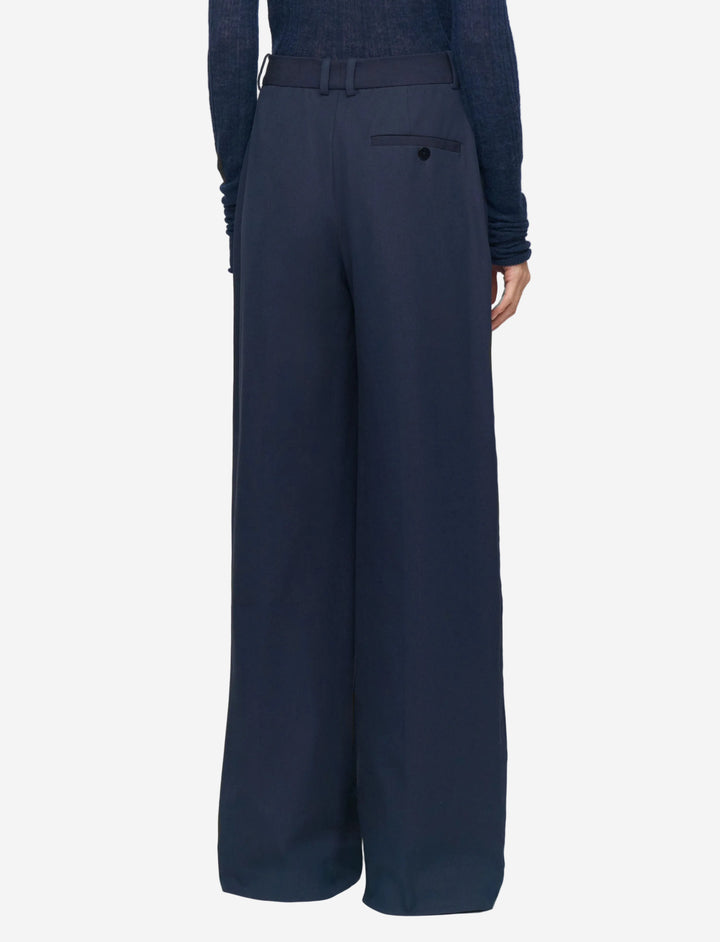 Navy blue wide-leg pants worn by a person on a light gray background